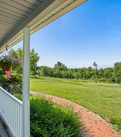 Enjoy expansive views and outdoor living from this welcoming wraparound porch, perfect for relaxation or entertaining.