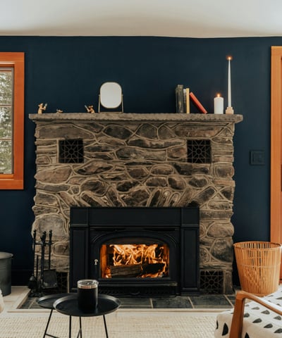 Cozy living area featuring a stone fireplace, large windows, and direct access to a snowy outdoor space.