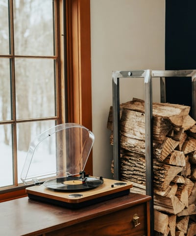Cozy space featuring a vintage turntable beside a neatly stacked pile of firewood, perfect for relaxation.