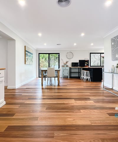 Spacious open-concept living area with warm wooden floors and abundant natural light, ideal for entertaining.