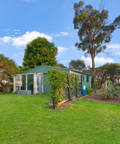 This property features a spacious backyard with greenery and a versatile outbuilding, perfect for various uses.