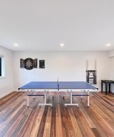Bright recreational space featuring a ping pong table, arcade machine, and dartboard for entertainment.