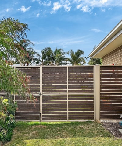 This property features a private outdoor space bordered by modern fencing and vibrant landscaping.