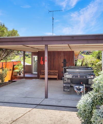 This property features a spacious carport, landscaped surroundings, and a unique architectural design, ideal for customization.