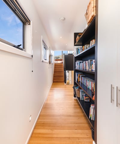Bright and inviting hallway features built-in shelving, leading to a spacious upper-level living area.