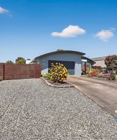 Beautifully landscaped exterior greets you, featuring a spacious driveway and inviting entrance to a modern home.