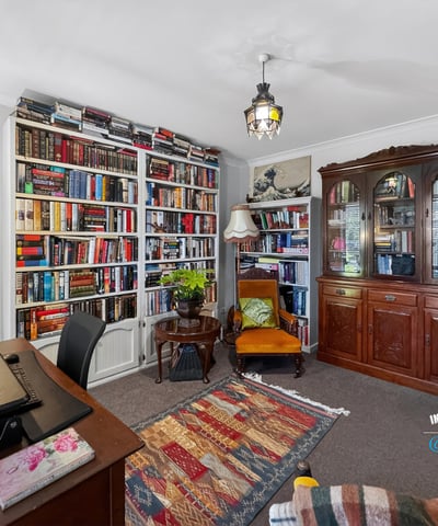 Cozy reading nook with expansive bookshelves and a versatile workspace, perfect for relaxation and productivity.