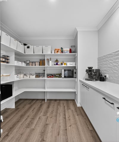 Discover a spacious pantry featuring smart shelving and modern appliances, perfect for organized meal prep.
