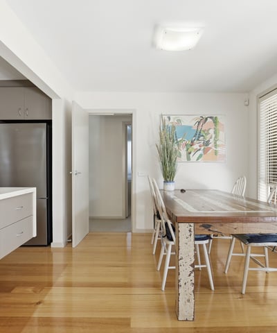 Bright and airy dining space featuring a rustic wooden table, modern kitchen amenities, and abundant natural light.