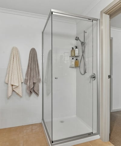 Bright and modern bathroom featuring a spacious walk-in shower and convenient storage options.
