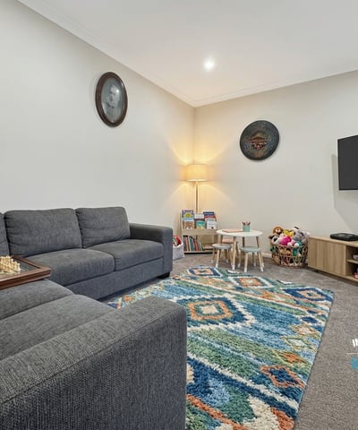 Bright, inviting living area featuring modern furnishings, a playful rug, and ample natural light throughout.