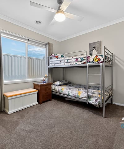 Cozy bedroom featuring a bunk bed, ample natural light, and versatile storage options.