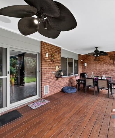 Spacious covered patio perfect for outdoor dining, featuring ceiling fans and a view of the lawn.