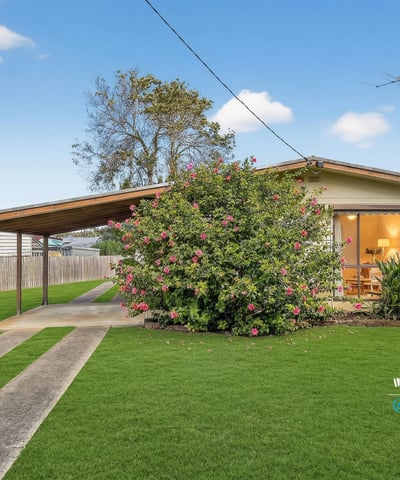 Cozy home featuring expansive green lawns and a covered carport, ideal for outdoor living.