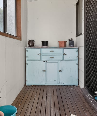 Bright and inviting enclosed porch featuring a rustic blue cabinet, perfect for additional storage and decor.