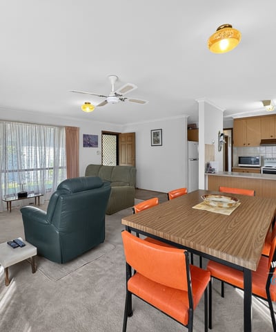Spacious living area with natural light, featuring a dining space and a functional kitchen layout.