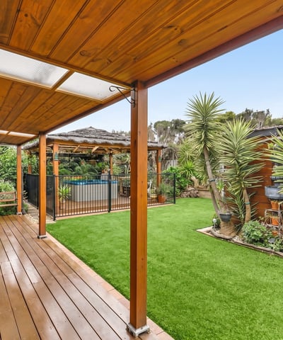 Discover a spacious outdoor oasis featuring sleek decking, vibrant greenery, and a refreshing pool area.