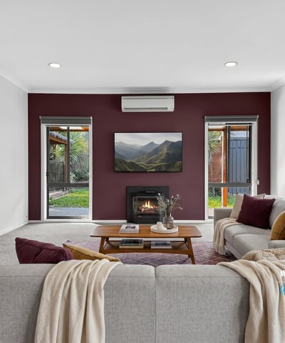 Cozy living room with modern features, featuring a fireplace and large windows overlooking a private outdoor space.