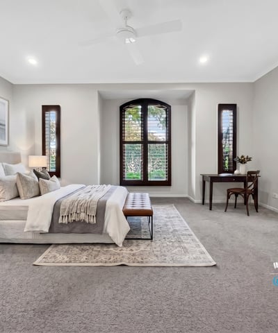 Spacious master bedroom featuring large windows, plush carpeting, and a cozy reading nook.