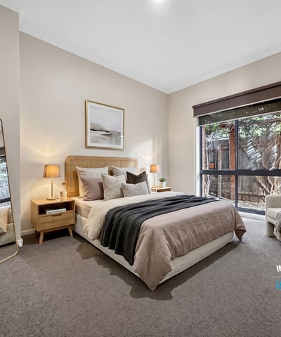 Bright and inviting bedroom featuring large windows, modern decor, and a cozy reading nook for relaxation.