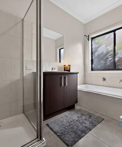 Modern bathroom featuring a spacious shower, separate tub, and large window for natural light.