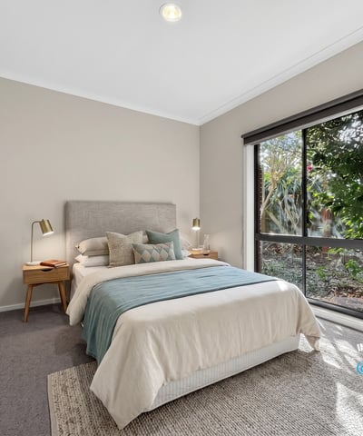 Bright bedroom featuring large windows, cozy furnishings, and a peaceful view of the outdoor greenery.