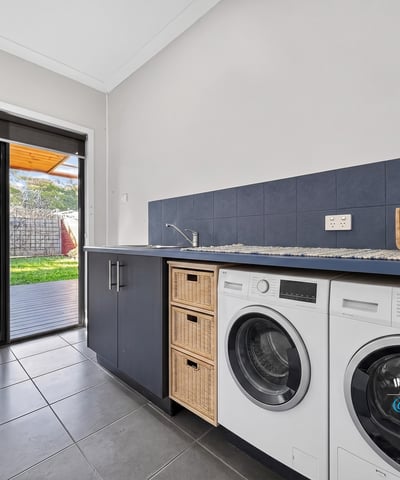 Bright laundry room featuring modern appliances and direct access to a shaded outdoor area.