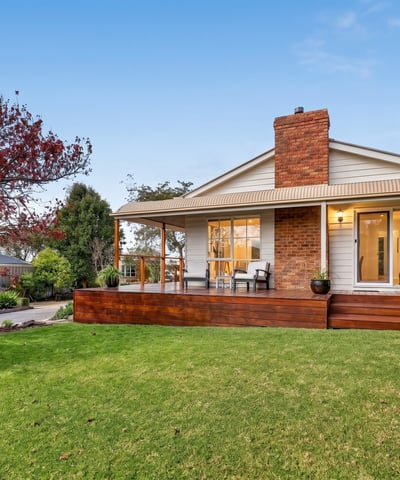 Nestled on a spacious lawn, this home features a welcoming porch and abundant outdoor greenery.