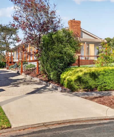 This spacious home features a picturesque landscape, inviting driveway, and ample outdoor space for entertaining.