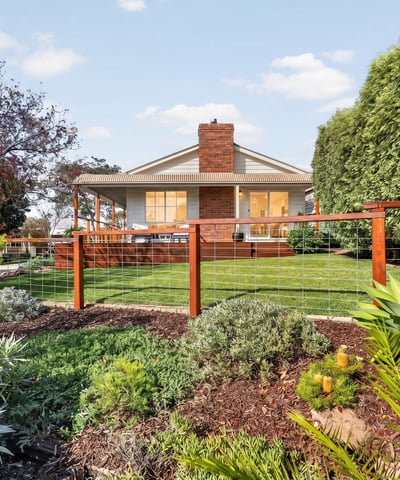 Discover a beautifully landscaped property featuring a spacious backyard with vibrant greenery and ample outdoor space.