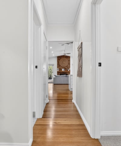 Bright, inviting hallway leading to a spacious living area, showcasing modern design and warmth throughout.