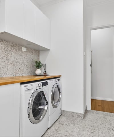 Bright laundry area featuring modern appliances, streamlined cabinetry, and a clean, functional design.