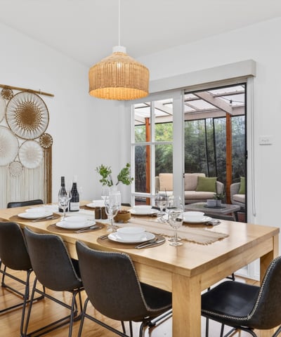 Bright dining area features a spacious table, inviting decor, and views of a cozy outdoor space.