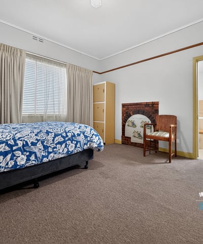 Spacious bedroom featuring natural light, a cozy seating area, and convenient access to an ensuite bathroom.