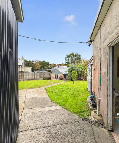 Spacious backyard with landscape potential, featuring accessible pathways and neighboring properties for a vibrant community feel.