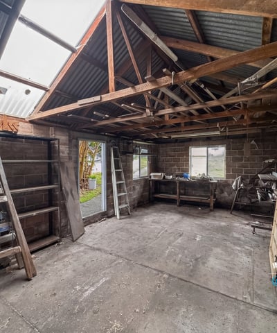 Spacious workshop with ample storage potential, featuring high ceilings and natural light for creative projects.