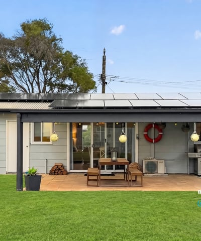 This modern home features a spacious outdoor area with solar panels and a built-in grill for entertaining.