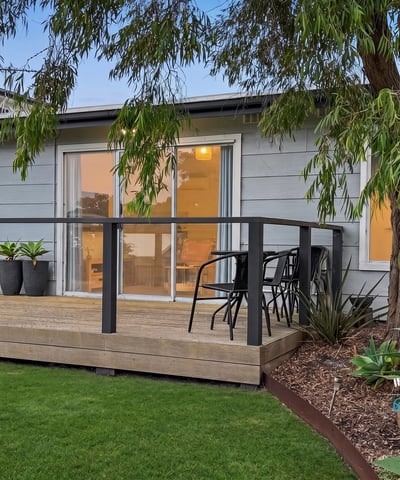 This property features a spacious deck surrounded by lush landscaping, perfect for outdoor relaxation and entertaining.