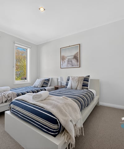 Bright and inviting bedroom with ample natural light, featuring twin beds and modern aesthetics.