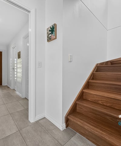 Modern entryway featuring open space, inviting natural light, and a warm wooden staircase.