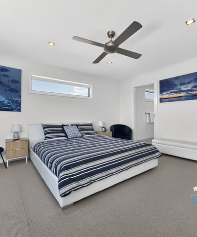 Light-filled bedroom featuring modern decor, ample space, and beautiful ocean-themed artwork for a refreshing atmosphere.