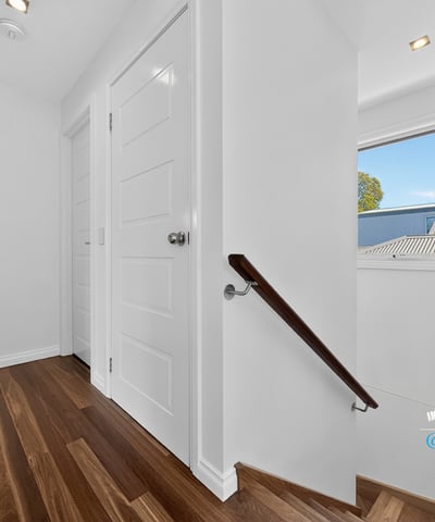 Bright and inviting hallway featuring warm wood flooring and ample natural light from the window.