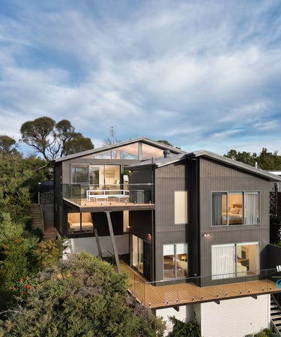 Contemporary home nestled in nature, featuring expansive decks and large windows that invite abundant natural light.