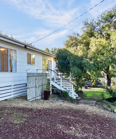 This inviting home features a spacious yard and a welcoming entrance surrounded by lush greenery.