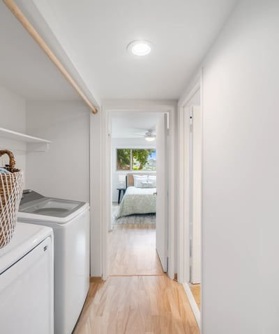 Spacious laundry area leading to a well-lit bedroom, featuring modern appliances and ample storage solutions.