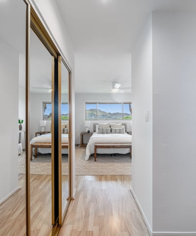Bright and airy corridor leads to a spacious bedroom with mountain views and abundant natural light.