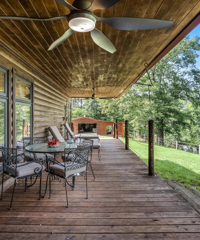 Spacious covered porch with ample seating, perfect for enjoying panoramic views of the surrounding landscape.