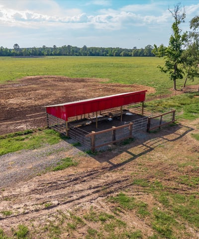 Versatile property featuring a spacious open field with a covered structure, perfect for agricultural or recreational use.
