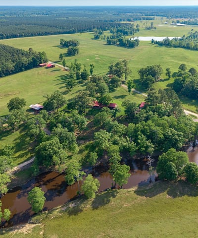 Expansive rural property with lush greenery, waterways, and multiple outbuildings, ideal for diverse development opportunities.