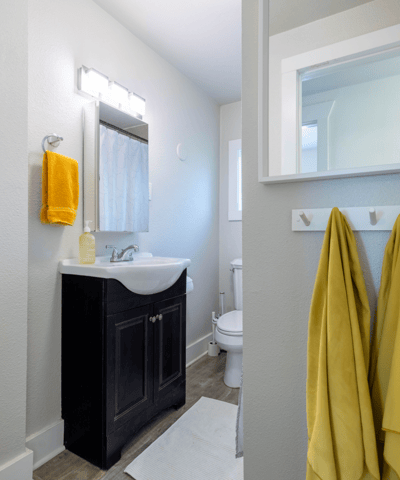 Bright and clean bathroom featuring modern fixtures, ample storage, and vibrant yellow accents for a fresh look.